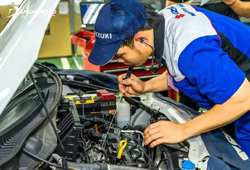 Một thợ máy đang kiểm tra động cơ ô tô bằng ống nghe trong quá trình bảo dưỡng định kỳ