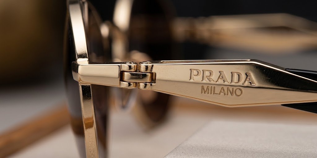 Chi tiết càng kính kim loại bản dẹp với logo Prada khắc nổi của PR 65ZS ZVN09T